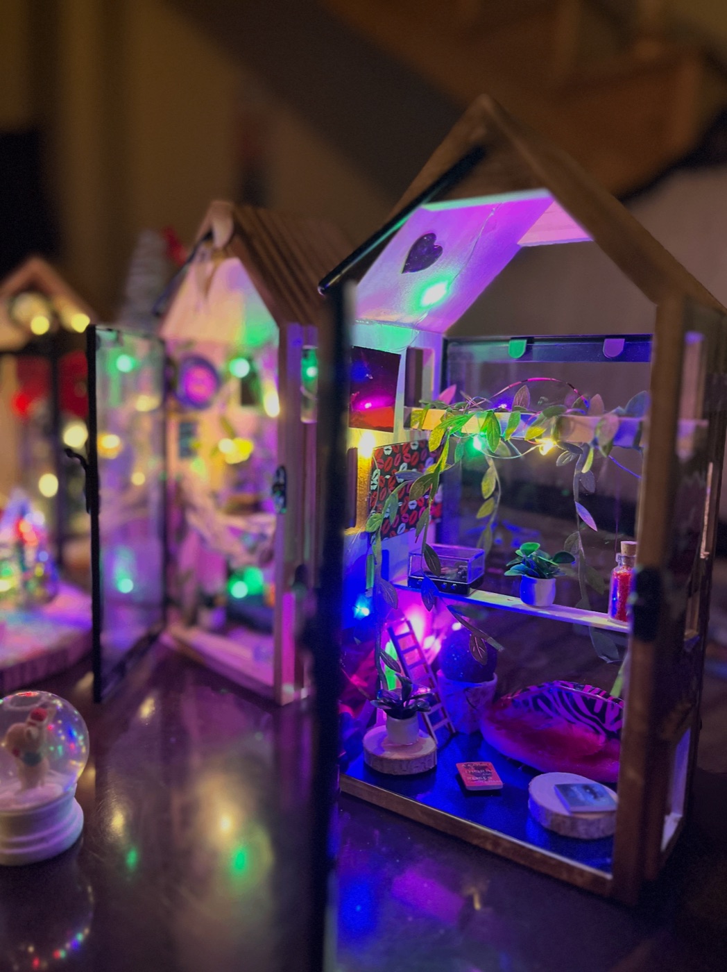 Miniature house diorama glowing with fairy lights, tiny plants and books